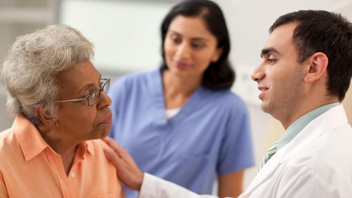 Two clinicians talking to an elderly woman