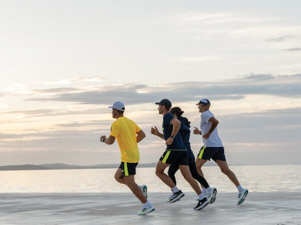 Four participants in the run are running together on the beach.