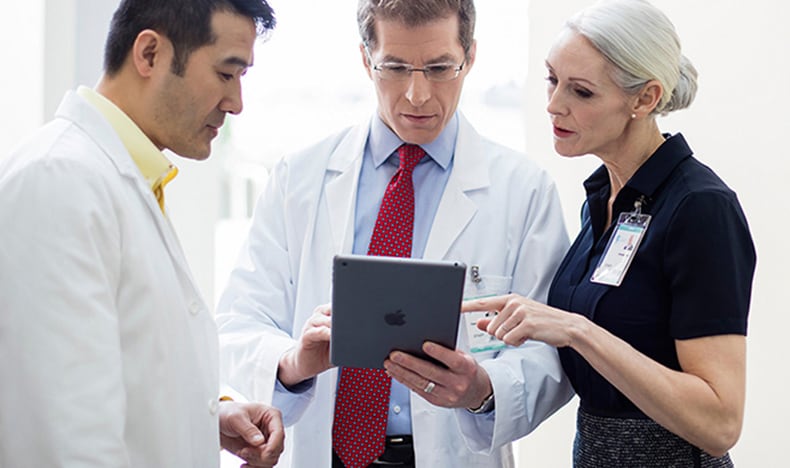 Healthcare administrators discussing data on a tablet