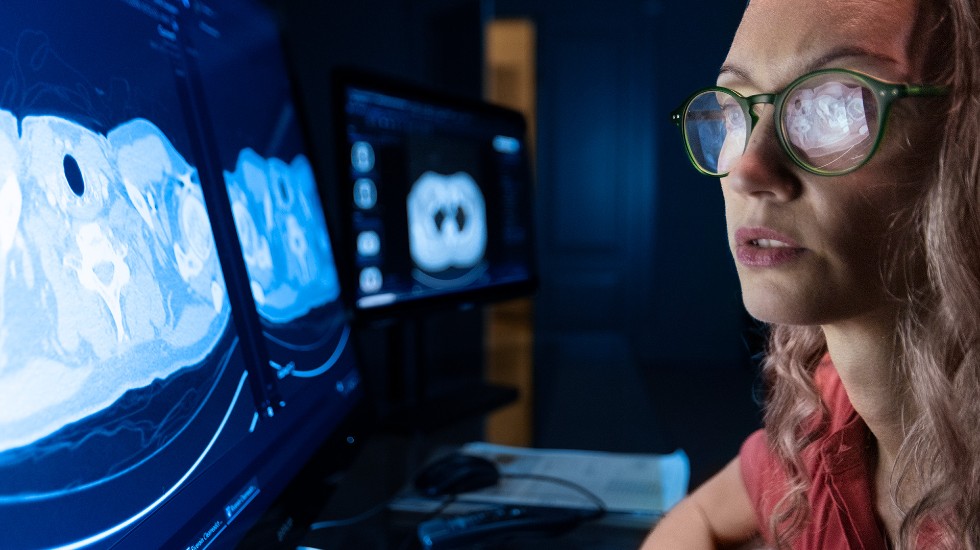 A female radiologist looking at a screen using an AI application