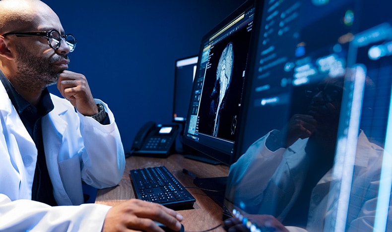 A male radiologist looking at a screen using an AI application