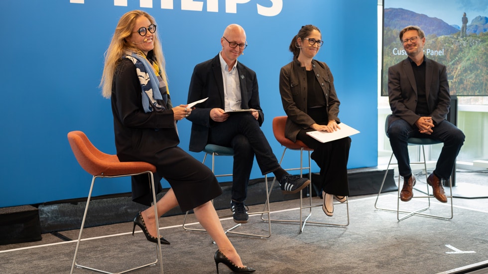 Four healthcare leaders sit on chairs during a Sustainability Education Session panel at Philips, including Clara Sattler de Sousa e Brito, Robert Metzke, Joana Lamego and Richard Hixson.