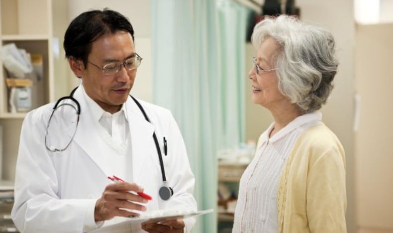 A doctor reviews a medical chart with a smiling middle-aged patient