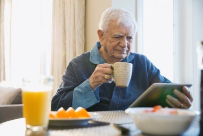 Digital health technology|Senior man with digital tablet having coffee at home