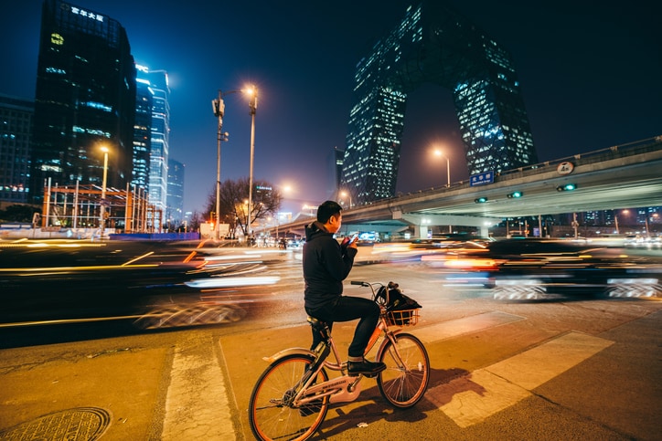 Man Looking at Mobile Phone on a bike at Night