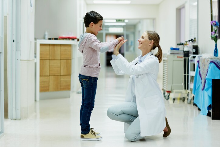 Doctor giving high-five to boy in corridor