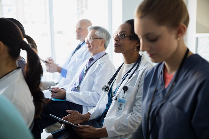 Doctor with digital tablet listening in seminar audience