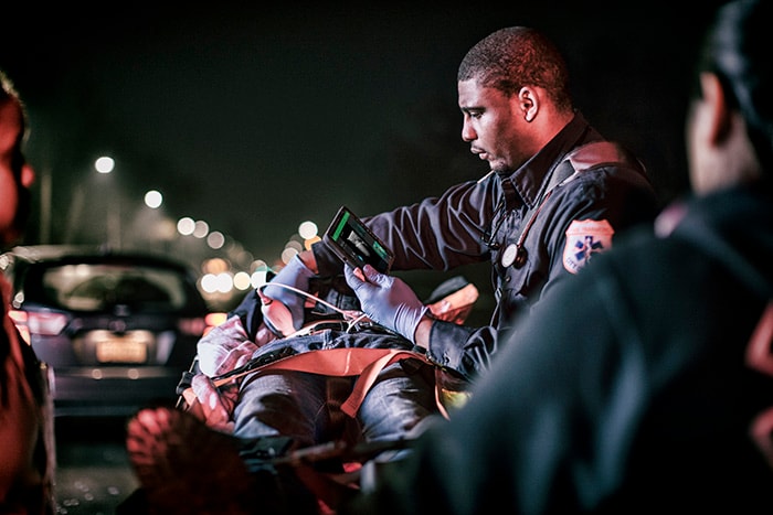 Paramedic examines patient using mobile ultrasound at the trauma scene
