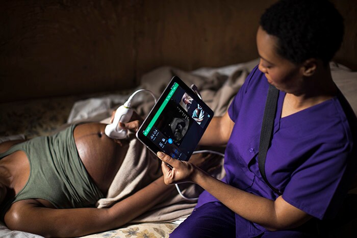 Midwife in Africa examines a pregnant woman while consulting an obstetrician remotely