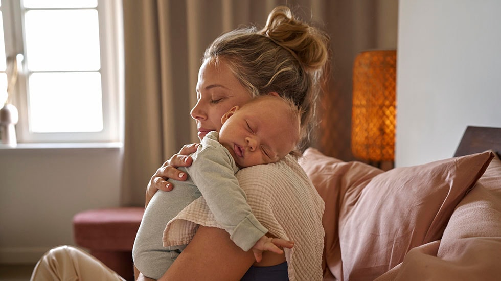 Holding sleeping baby in bed